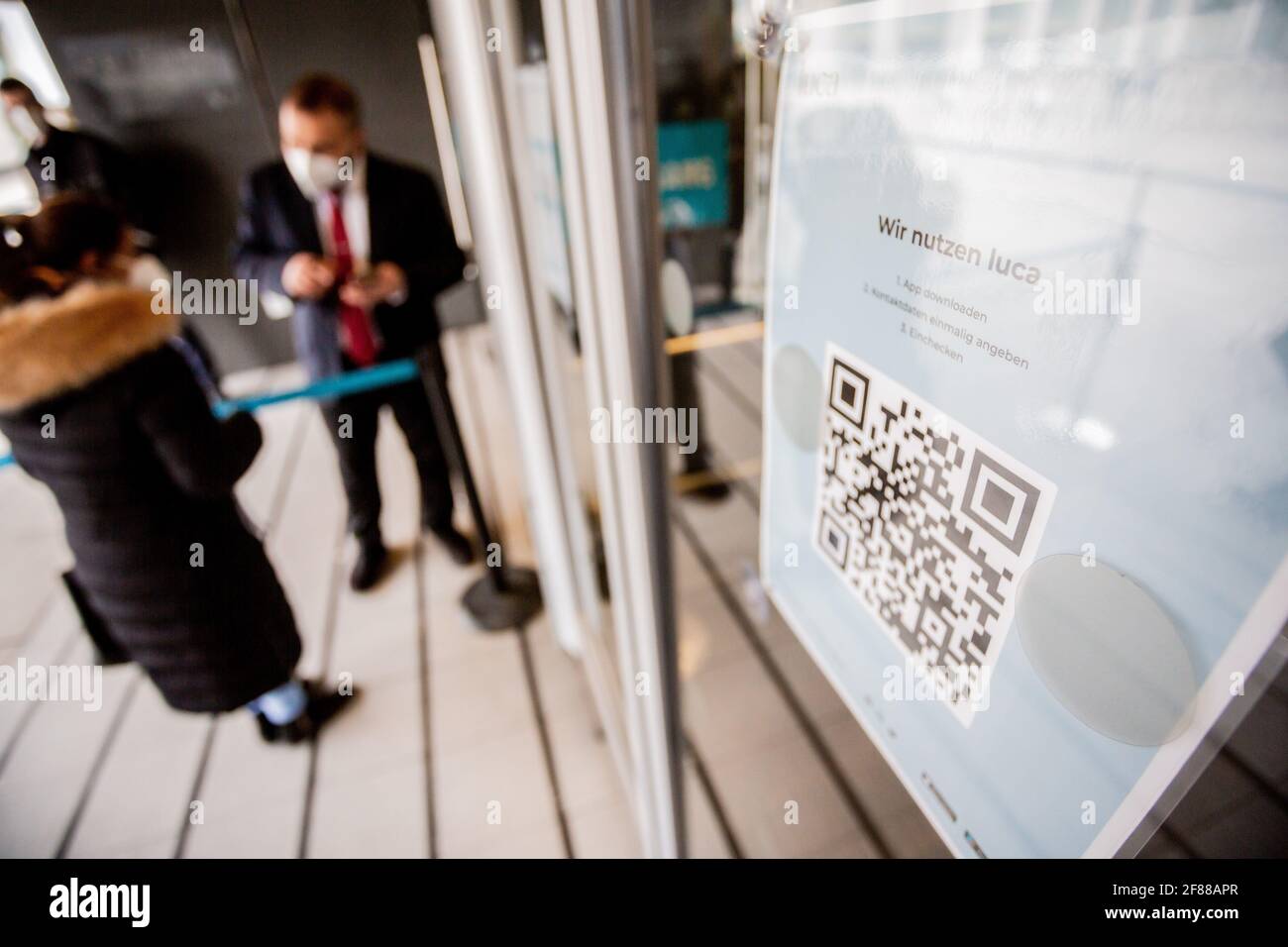 Berlin, Deutschland. April 2021. Ein QR-Code zum Herunterladen der Luca App hängt am Eingang eines Bekleidungshauses am Alexanderplatz. Die App dient zur Bereitstellung von Daten für eine mögliche Kontaktverfolgung. Quelle: Christoph Soeder/dpa/Alamy Live News Stockfoto
