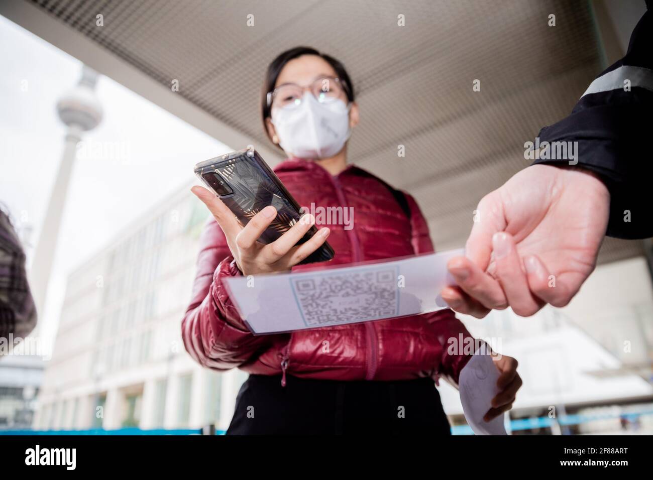 Berlin, Deutschland. April 2021. Ein Kunde scannt einen QR-Code am Eingang eines Bekleidungshauses am Alexanderplatz vor einem Wachmann mit der Luca-App ein. Die App dient zur Bereitstellung von Daten für eine mögliche Kontaktverfolgung. Quelle: Christoph Soeder/dpa/Alamy Live News Stockfoto