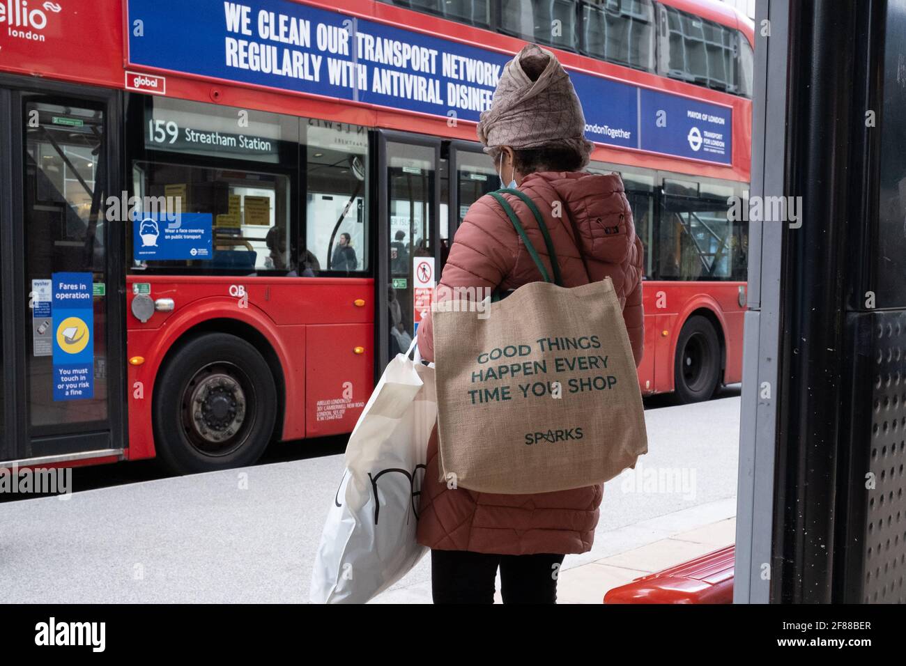 London, England, 12. April 2021. Eine Frau, die in der Oxford Street auf einen Bus wartet, da die Beschränkungen für Covid gelockert werden, sodass nicht unbedingt erforderliche Geschäfte geöffnet werden können. Fotograf: Brian Duffy Stockfoto