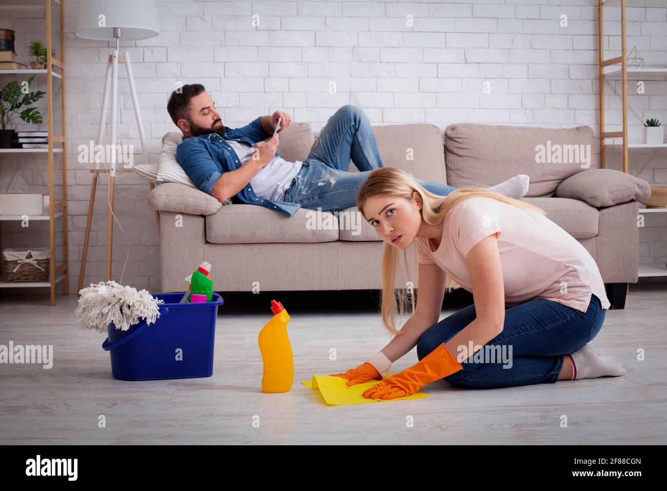 Gleichgültigkeit, Faulheit, Hausarbeit und Chauvinismus. Traurige Frau Hausfrau gewaschen Fußböden Stockfoto