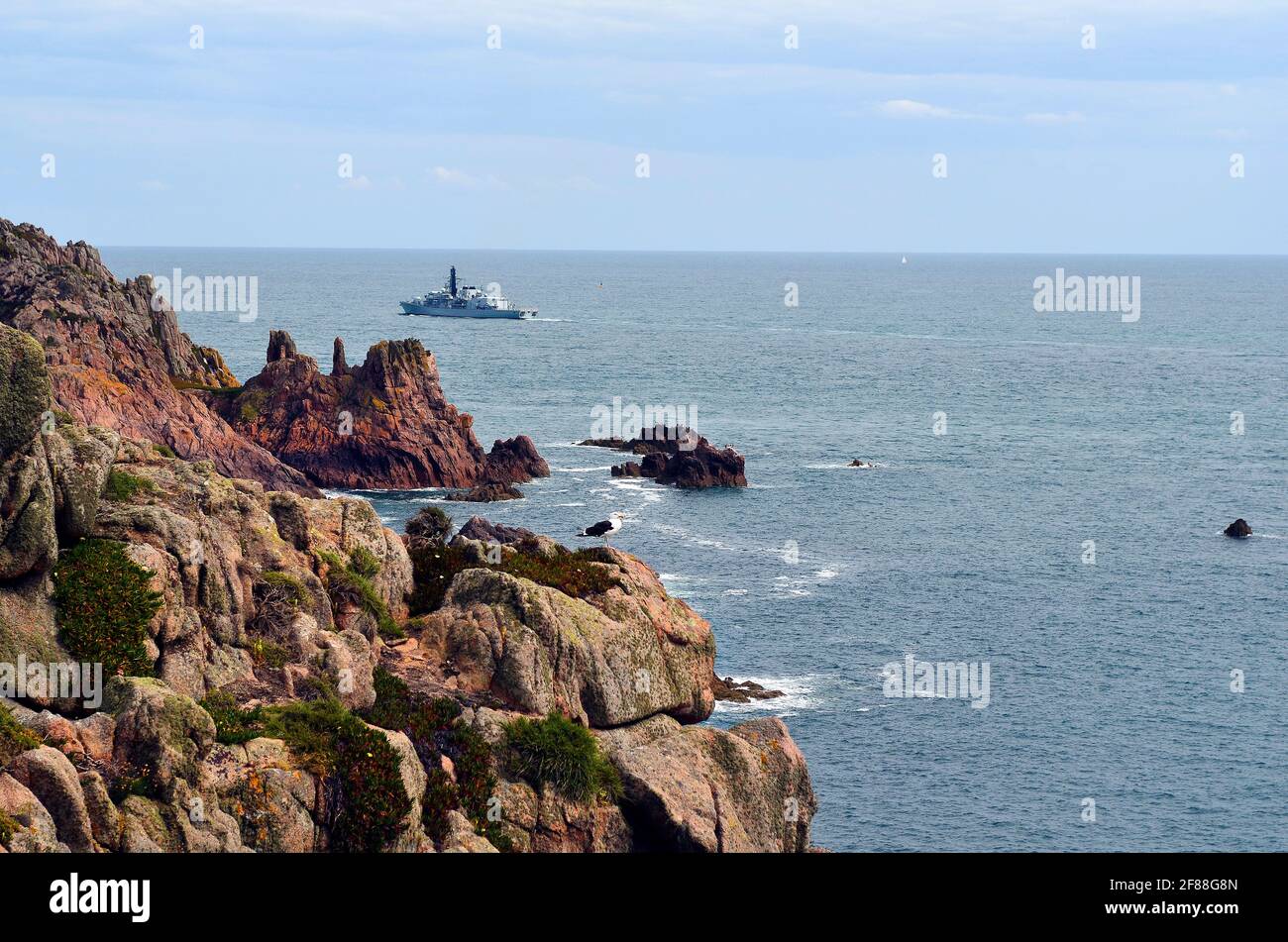 Großbritannien, Jersey, Rocky Coast und Kriegsschiff auf der Kanalinsel im Ärmelkanal Stockfoto