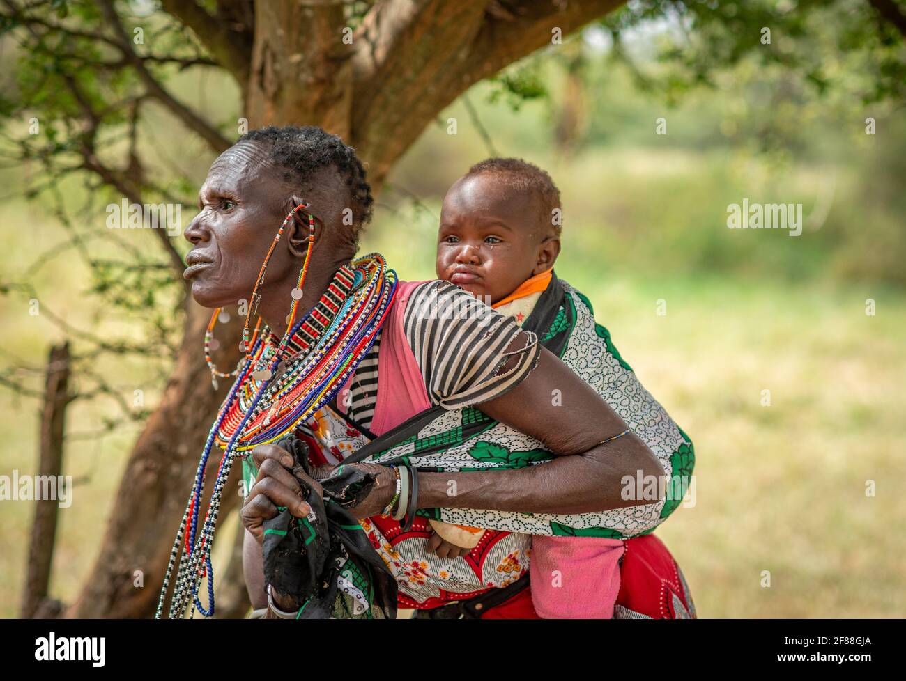 Traditionelle afrikanische Maasai-Frau mit Baby auf dem Rücken gewickelt Stockfoto