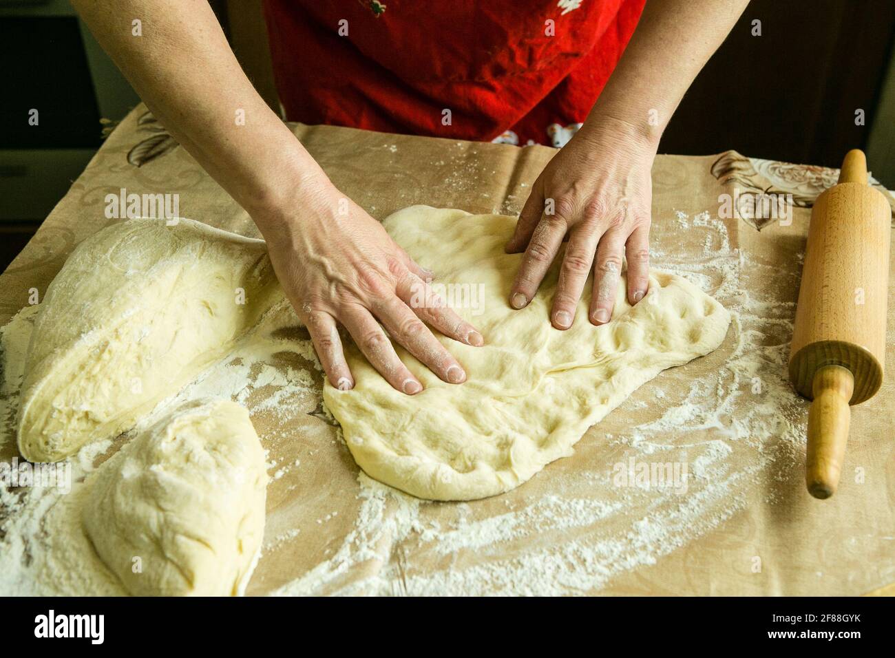 Mamas Kuchen. Weibliche Hände bereiten den Teig mit einem Nudelholz für den Kuchen vor. Kochen während der Quarantäne. Stockfoto