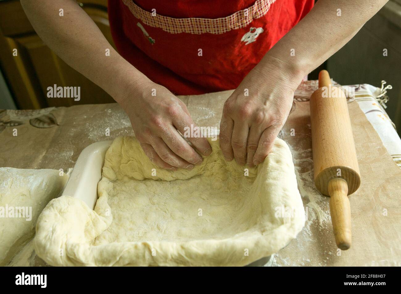 Mamas Kuchen. Weibliche Hände geben den Teig in die Form. Kochen während der Quarantäne. Stockfoto