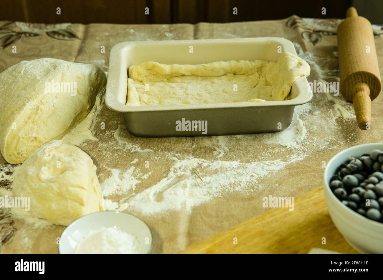 Mamas Kuchen. Der Teig wird in eine Backform gegeben. Sie können die Füllung verteilen. Kochen während der Quarantäne. Stockfoto