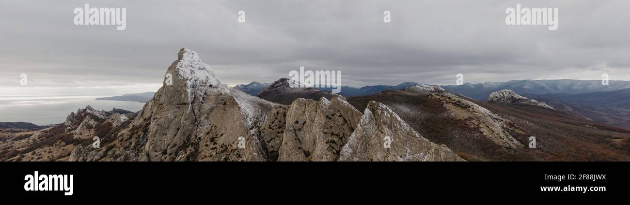 Panorama der Berggipfel im Schnee mit bergigen Gelände Meer und Himmel im Hintergrund. Stockfoto