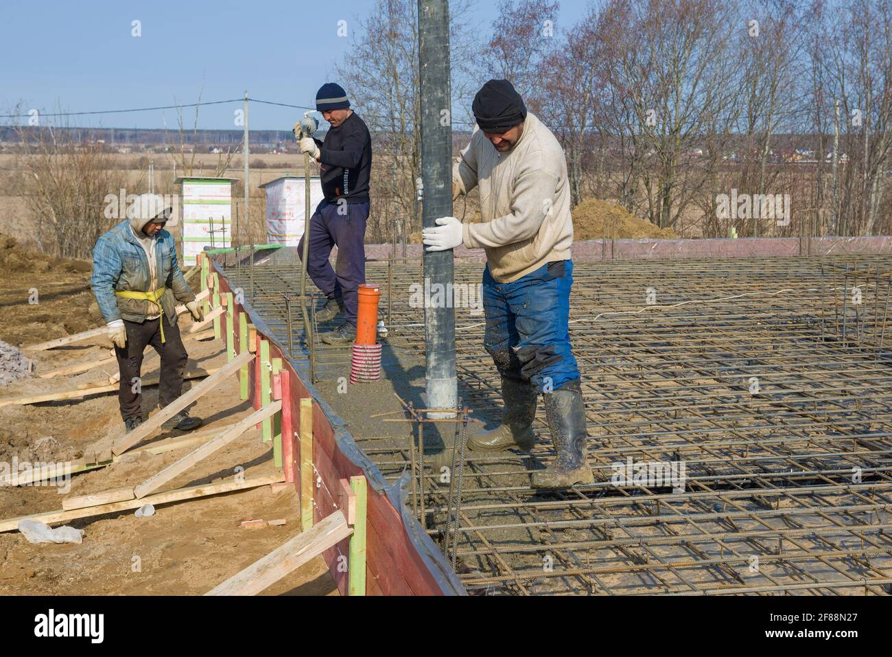 LENINGRAD, RUSSLAND - 28. MÄRZ 2021: Wanderarbeiter legen an einem sonnigen Frühlingstag den Grundstein für den Bau einer Landhütte Stockfoto