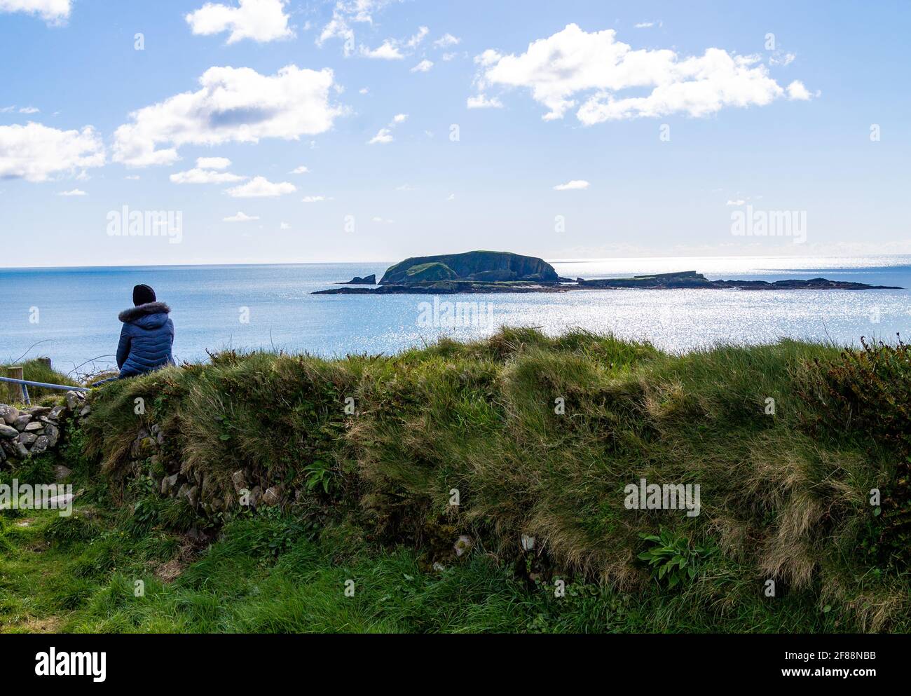 Die Person saß auf der Trockensteinmauer und blickte auf das Meer. Stockfoto