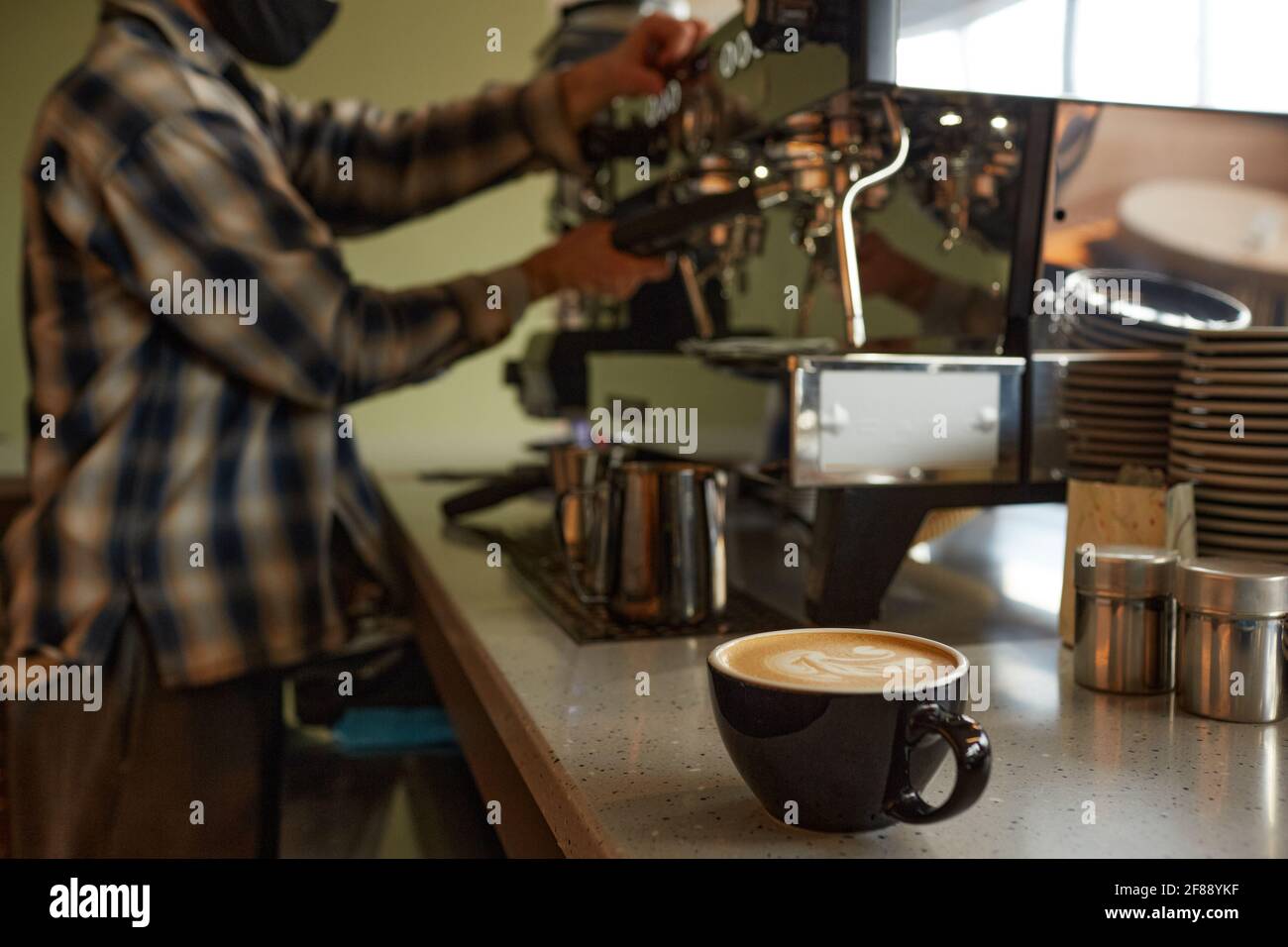 Nahaufnahme der Kaffeetasse an der Theke im Café oder Café mit unerkennbarem Barista im Hintergrund, Kopierbereich Stockfoto