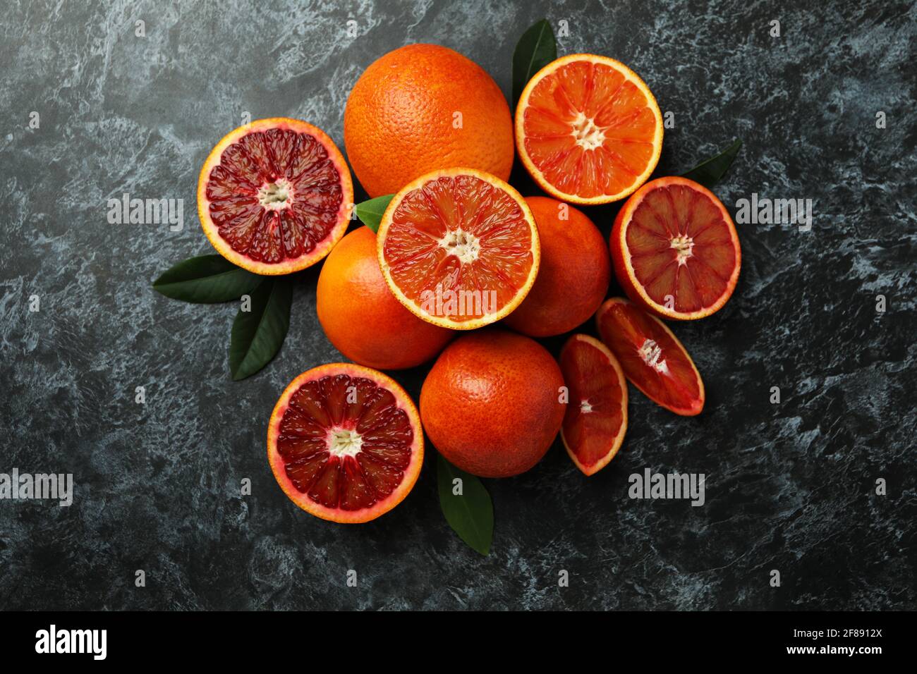 Rote Orangen und Blätter auf schwarzem rauchigen Hintergrund Stockfoto