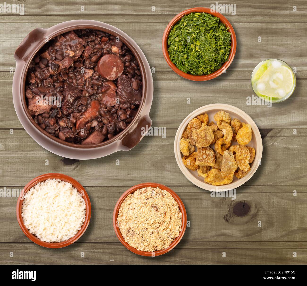 Typisch brasilianische Feijoada mit Caipirinha und Beilagen über Holz Tabelle Stockfoto