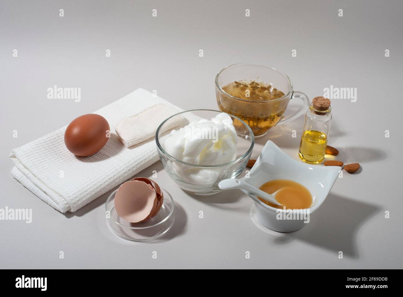 Inhaltsstoffe der Maske „Eierweiß“. Geschlagenes Eiweiß, Mandelöl, Honig, Kamillentee. Hausgemachte Kosmetik. Stockfoto