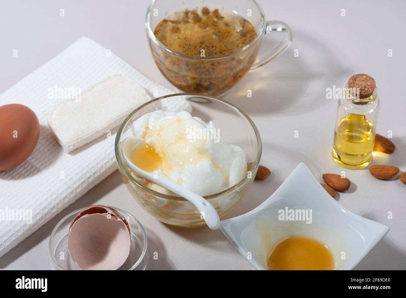 Inhaltsstoffe der Maske „Eierweiß“. Geschlagenes Eiweiß, Mandelöl, Honig, Kamillentee. Hausgemachte Kosmetik. Stockfoto