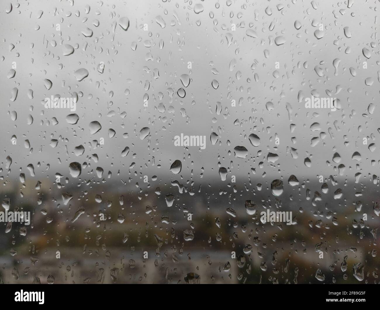 Natürliche Wassertropfen auf das Fensterglas nach Regen. Wassertropfen auf dem Fenster. Regnerisches Stimmungskonzept. Stockfoto