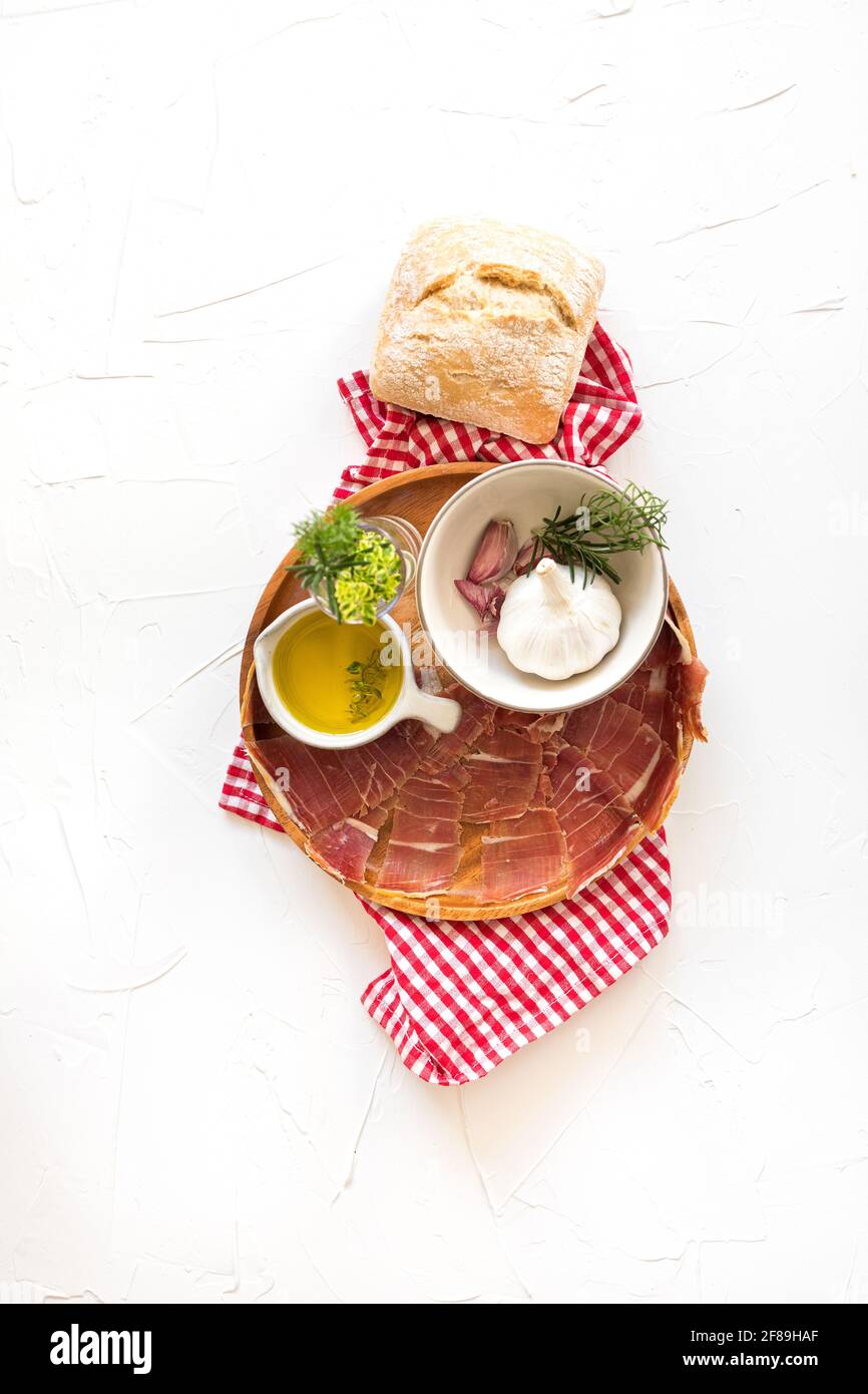 Ansicht der Zutaten von oben auf einem runden Holztablett bereit Für ein köstliches spanisches Picknick oder eine Vorspeise Mit Jamon serrano als Hauptteil Stockfoto