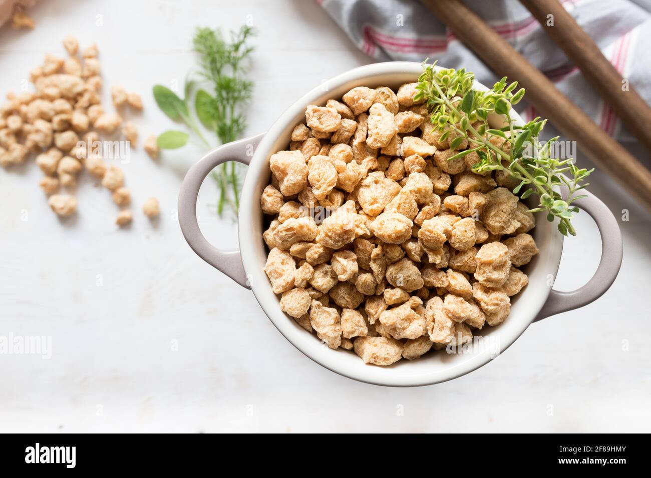 Nahaufnahme eines weißen Auflaufes voller roher Stücke Sojafleisch. Oben befindet sich ein aromatischer Zweig. Stockfoto