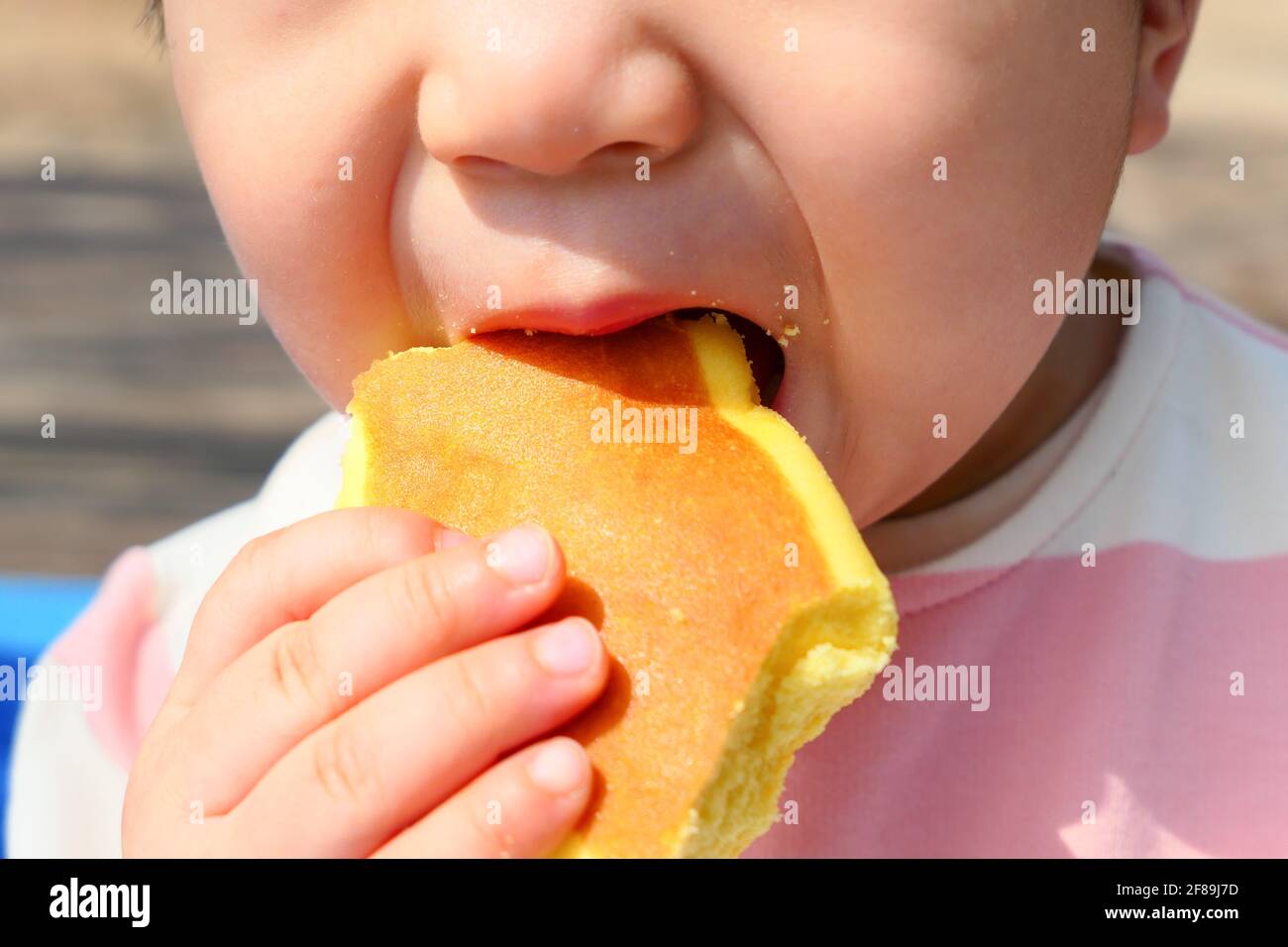 Asiatische Baby beißen Cheesalicious Biskuit (Brot essen) Stockfoto