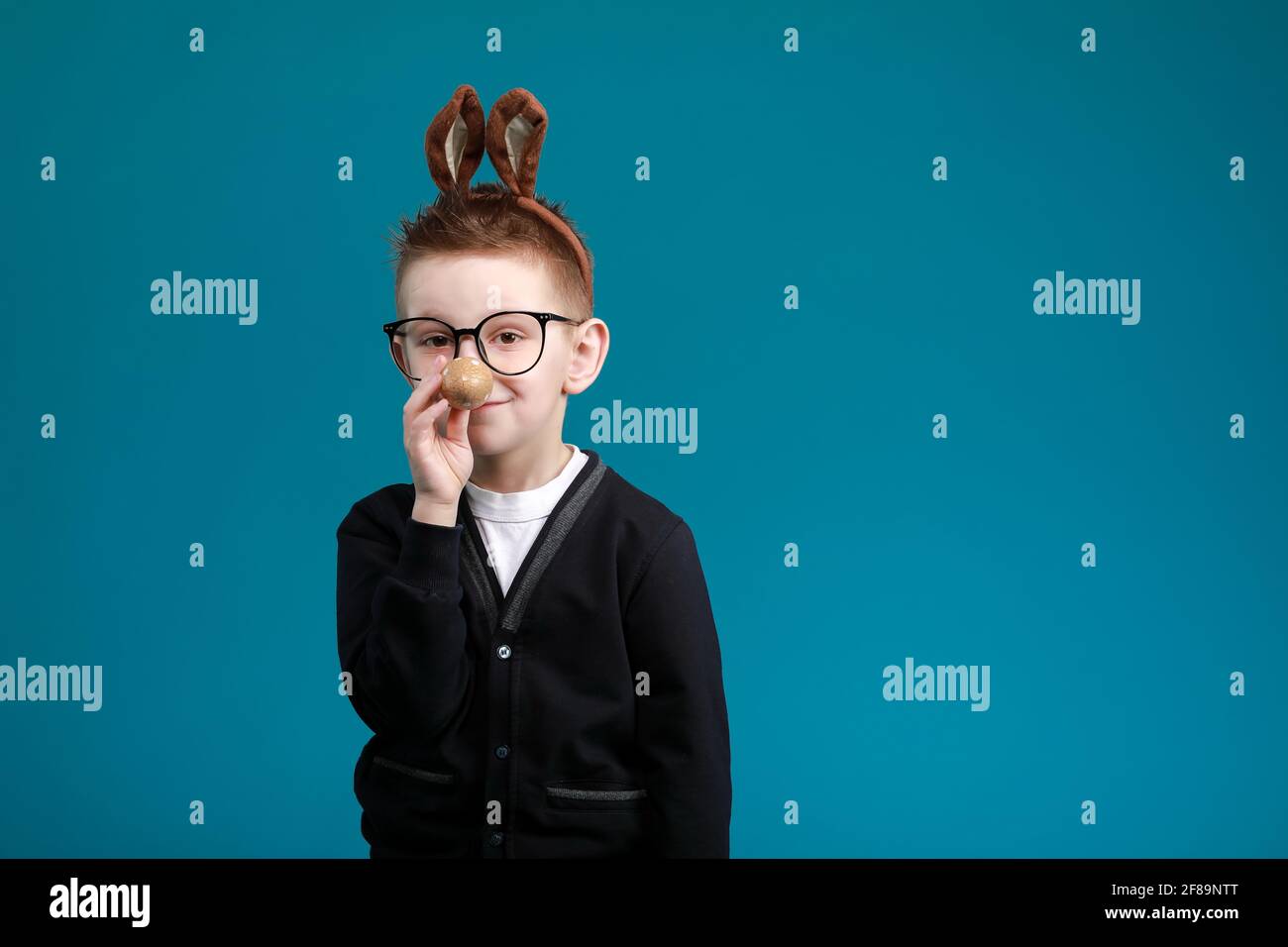 Fröhlicher Junge in Hasenohren auf dem Kopf auf blauem Studiohintergrund.  Aufgeregt verrückt lächelnd glückliches Kind in einer Brille. Osterblau  Farbe des Jahres malen Stockfotografie - Alamy