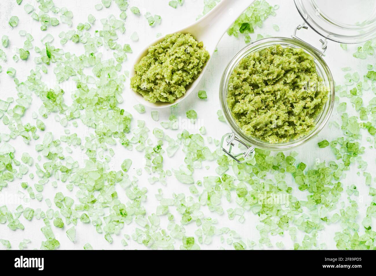 Grünes Aroma Badesalz in einem Glas auf grünem Badesalz Hintergrund. Spa, Hautpflegekonzept. Draufsicht, Kopierbereich. Selektiver Fokus Stockfoto