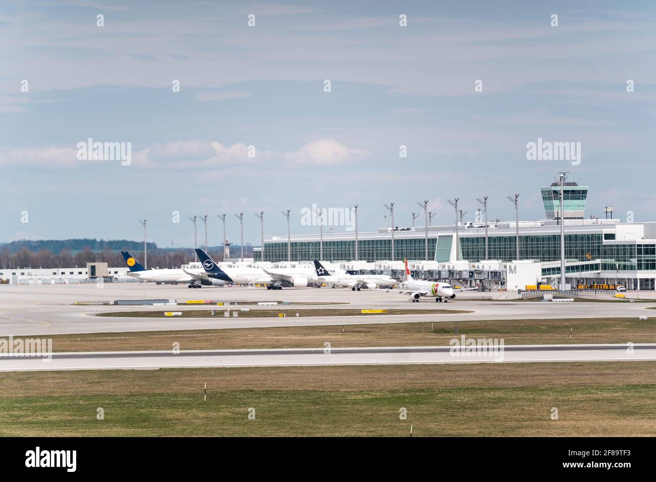 MÜNCHEN, DEUTSCHLAND - 10. Apr 2021: Die Flugzeuge stehen vor dem Flughafenterminal in München. Passagiere können an Bord gehen und das Flugzeug verlassen Stockfoto