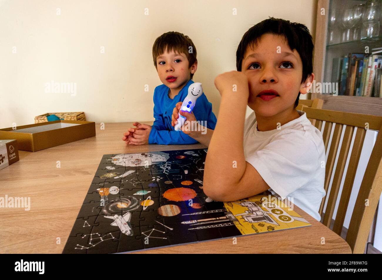 POZNAN, POLEN - 10. Apr 2021: Zwei junge Jungs spielen mit einem digitalen Stift von Albi und einem Kosmos-Puzzle an einem Holztisch. Das Set ist lehrreich und hilft KI Stockfoto