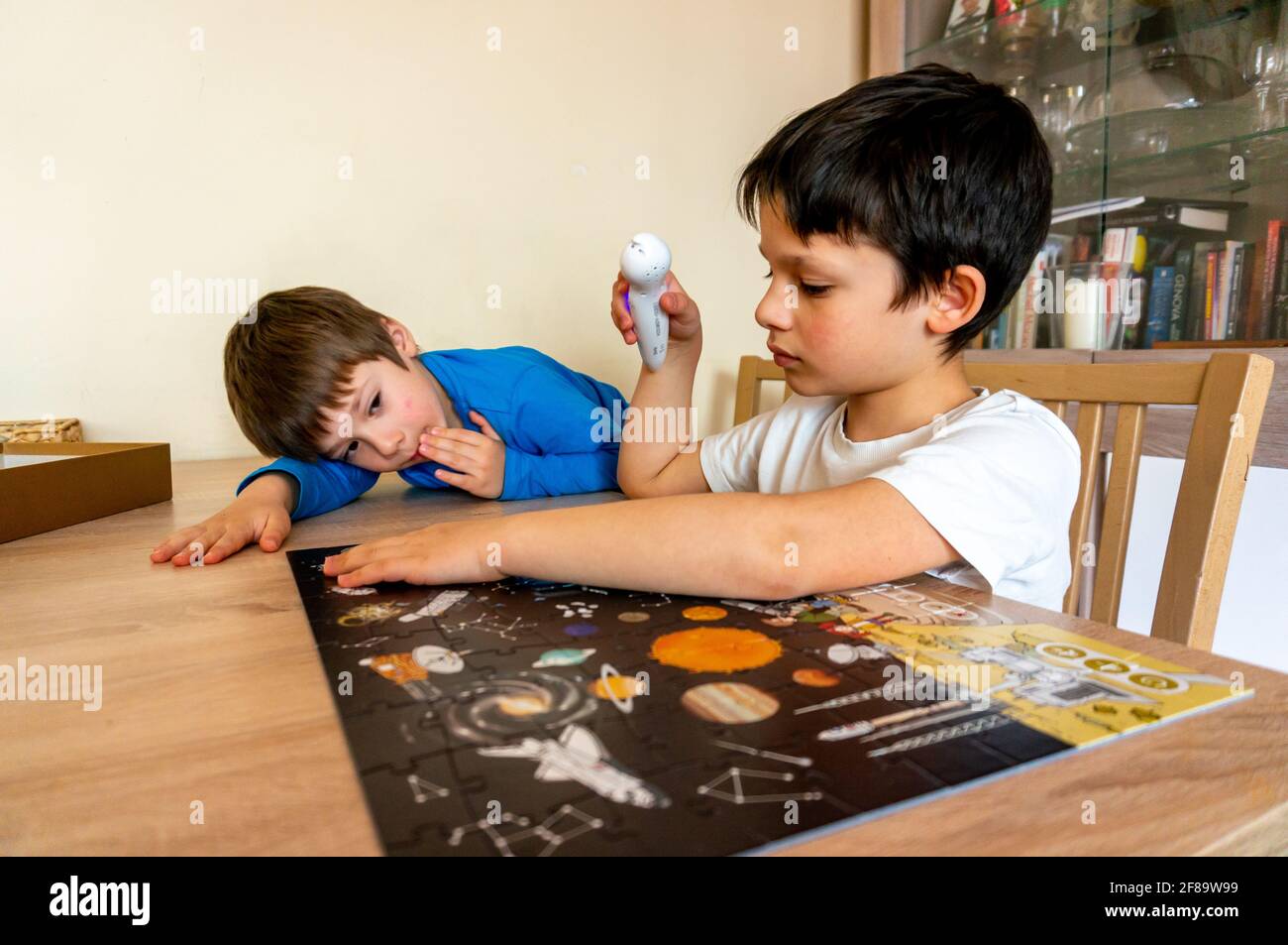 POZNAN, POLEN - 10. Apr 2021: Zwei junge Jungs spielen mit einem digitalen Stift von Albi und einem Kosmos-Puzzle an einem Holztisch. Das Set ist lehrreich und hilft KI Stockfoto