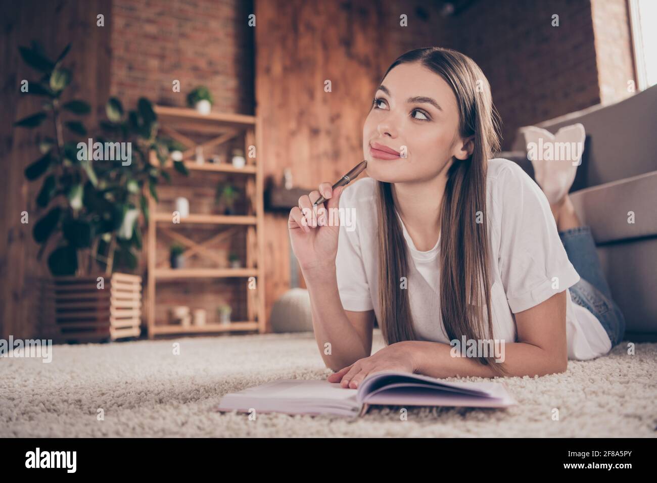 In voller Länge Foto von jungen attraktiven Frau glücklich positive Lächeln Lie Floor Think Dream Notizen schreiben Plan Notizbuch drinnen Stockfoto