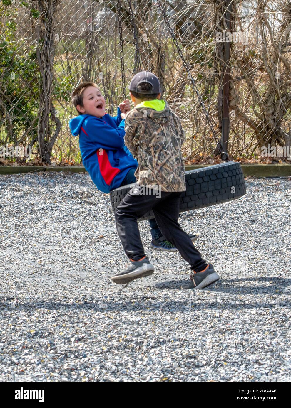 Zwei Brüder spielen auf einer Reifenschaukel auf einem Spielplatz Stockfoto