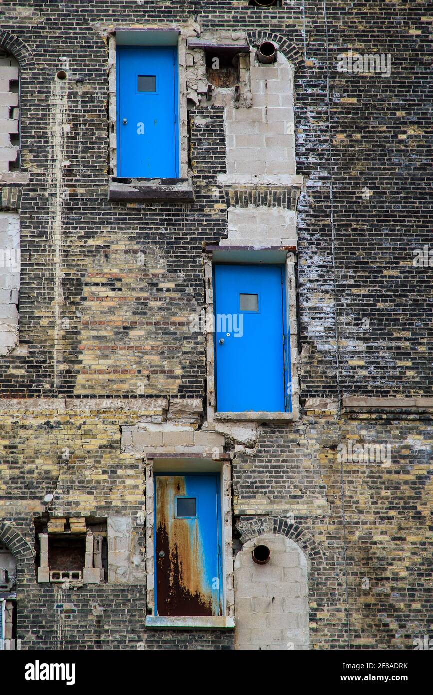 Drei lebendige blaue Türen an der Seite des verlassenen Gebäudes gemacht Von Brick in Milwaukee WI Stockfoto