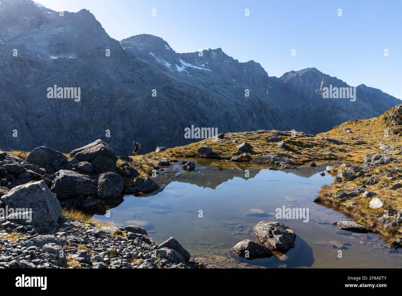 Wanderer passieren einen alpinen tarn in den Bergen Neuseelands Stockfoto