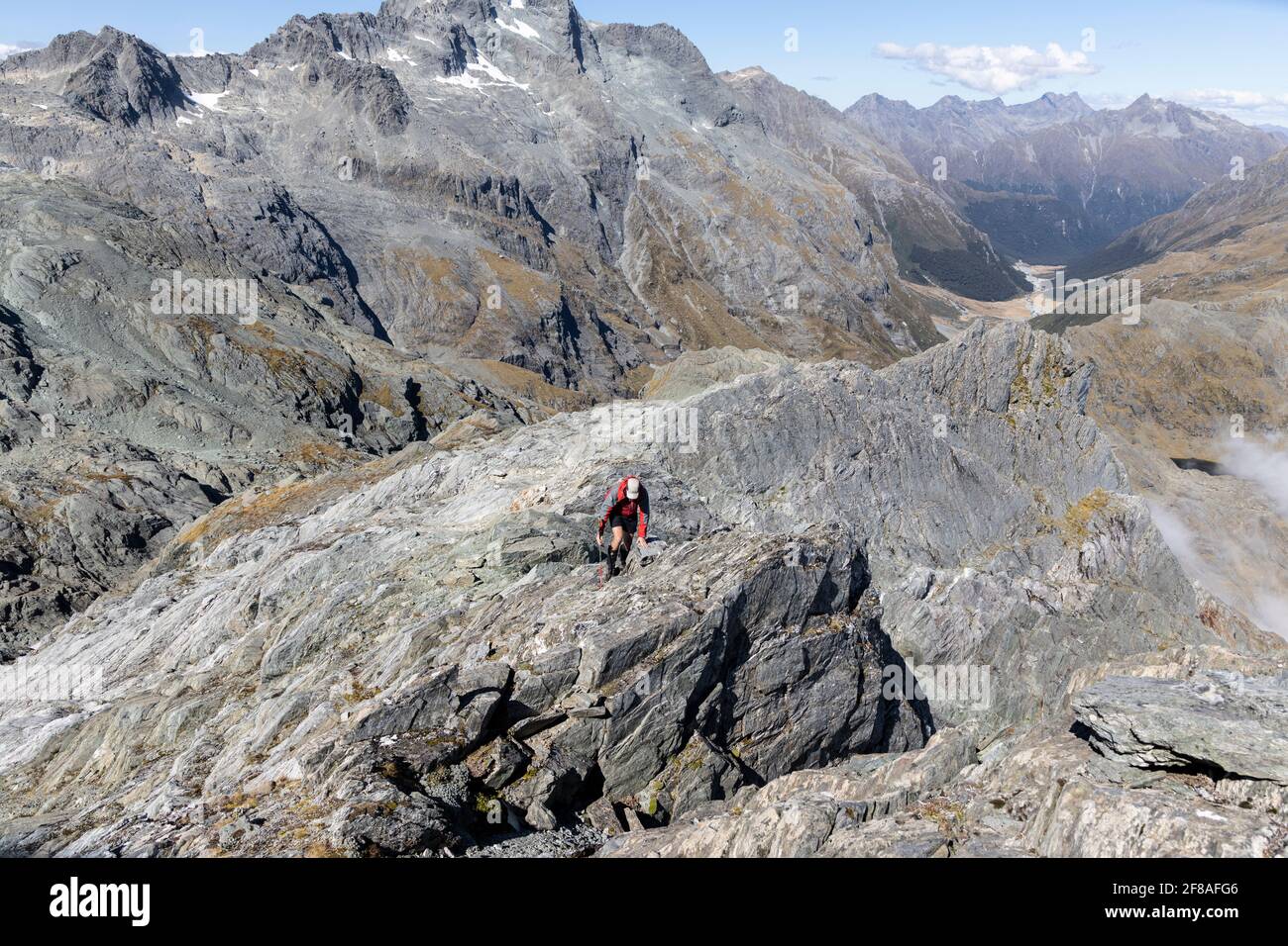 Mann klettert felsig und exponiert Ridge-line in South Island, Neuseeland Stockfoto