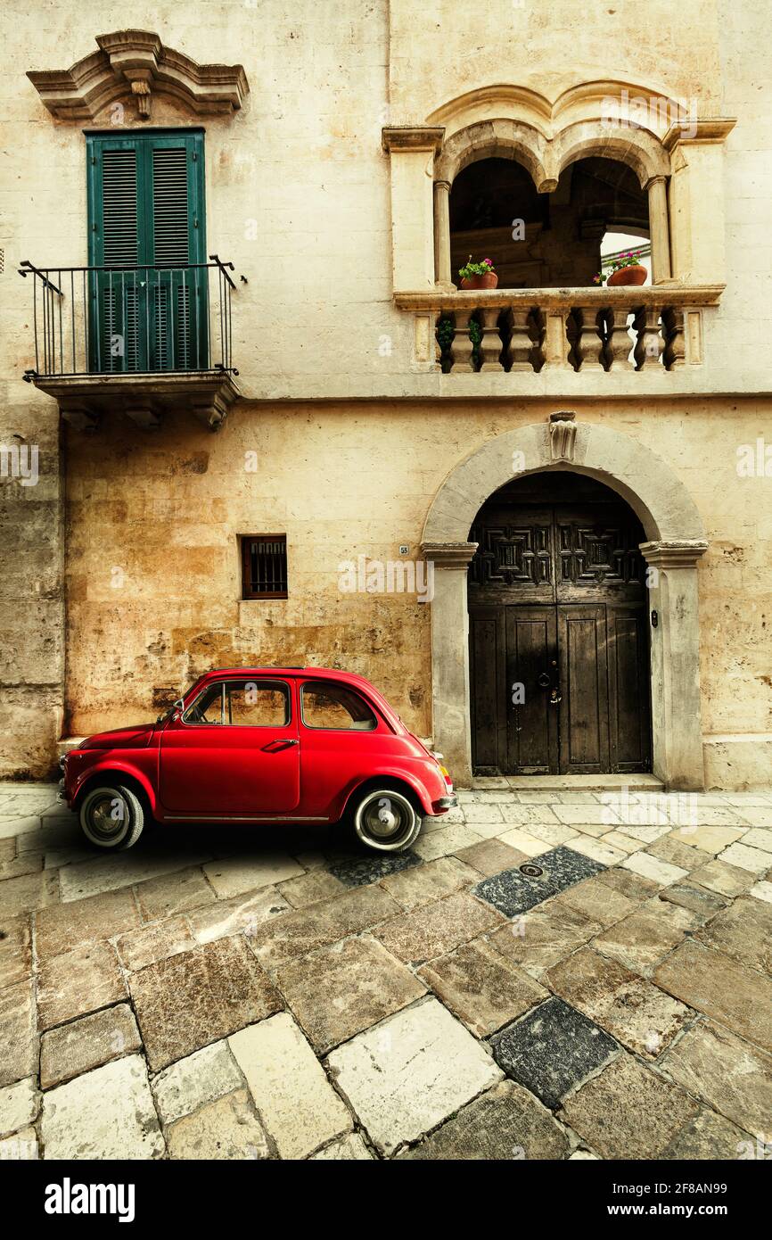 Altes rotes italienisches Auto, das vor einem historischen Haus geparkt wurde. Vintage-Atmosphäre. Stockfoto
