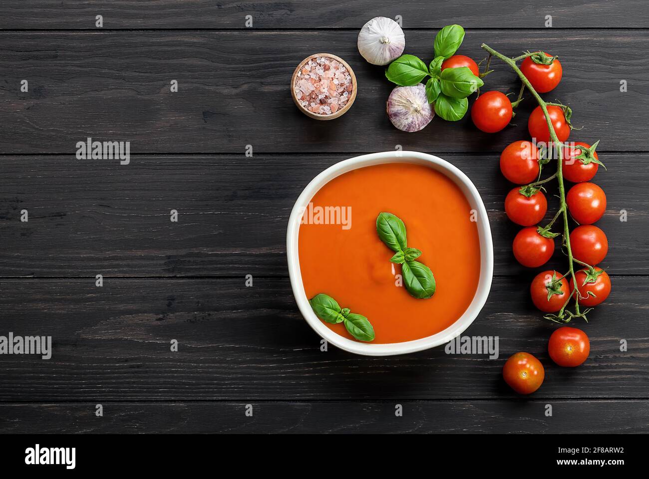 Tomatensuppe mit Knoblauch und Basilikum auf Holztisch. Vegetarisches Rezept, gesundes Mittagessen. Draufsicht, Platz kopieren Stockfoto