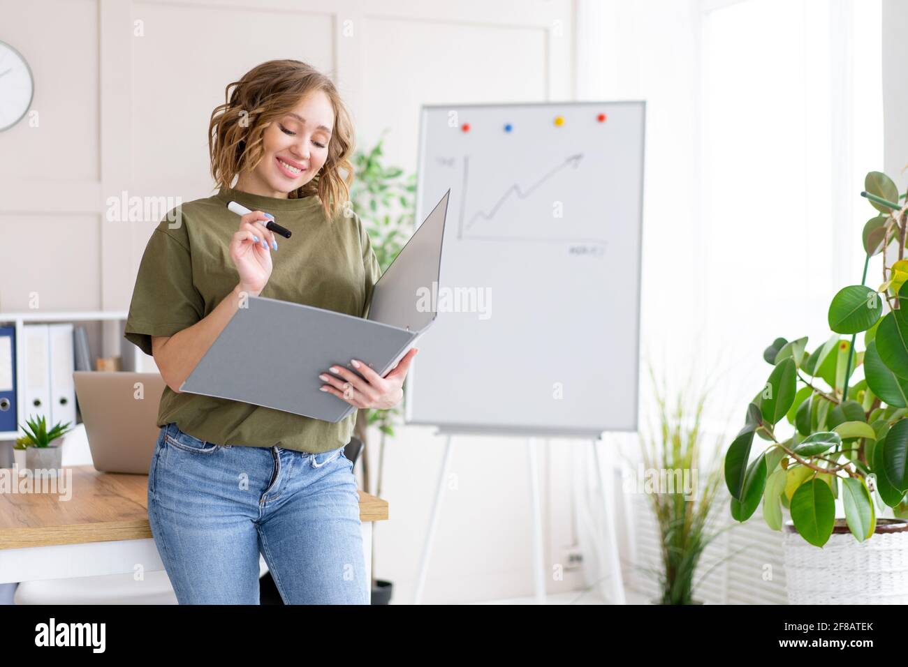 Geschäftsfrau hält Ordner für Papier schreiben Marker denken träumen neben Bürotisch stehen. Business Person femal ypoung Erwachsenen kaukasisch auf Modus Stockfoto