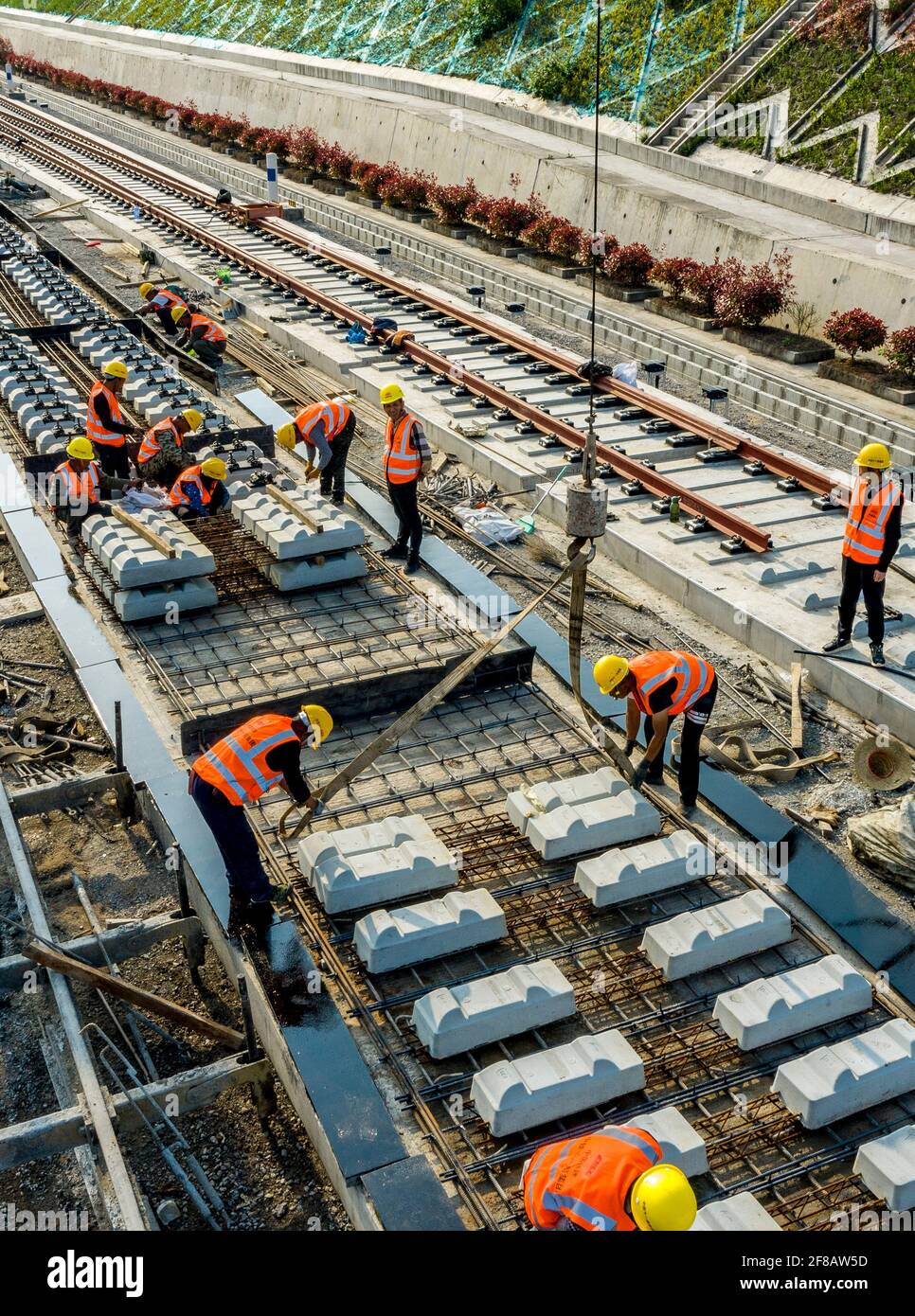 (210413) -- NANZHANG, 13. April 2021 (Xinhua) -- Luftfoto vom 12. April 2021 zeigt Arbeiter, die auf den ballastlosen Gleisen auf der Baustelle der Nanzhang Station der Hochgeschwindigkeitsbahn Zhengzhou-Wanzhou im Bezirk Nanzhang, der zentralchinesischen Provinz Hubei, arbeiten. Mit einer Geschwindigkeit von 350 km/h ist die Zhengzhou-Wanzhou-Eisenbahn, die Zhengzhou in der zentralchinesischen Provinz Henan und Wanzhou im südwestchinesischen Chongqing verbindet, ein wichtiger Teil des Eisenbahnsystems in den beiden Regionen. Im Vergleich zu herkömmlichen Strecken hat die ballastlose Strecke eine längere Lebensdauer und erfordert eine längere Lebensdauer Stockfoto