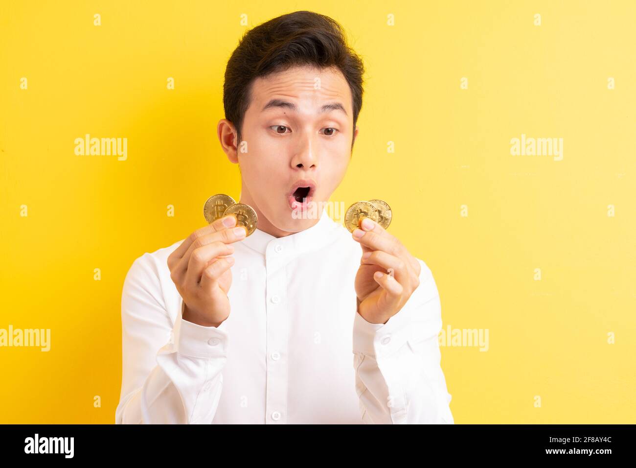 Asiatischer Geschäftsmann hält Bitcoin in der Hand und hat ein glückliches Gesicht Stockfoto
