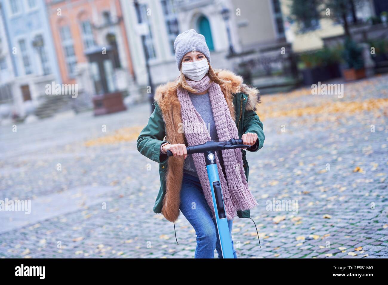 Frau trägt Gesichtsmaske und pendeln auf Roller in der Stadt Stockfoto