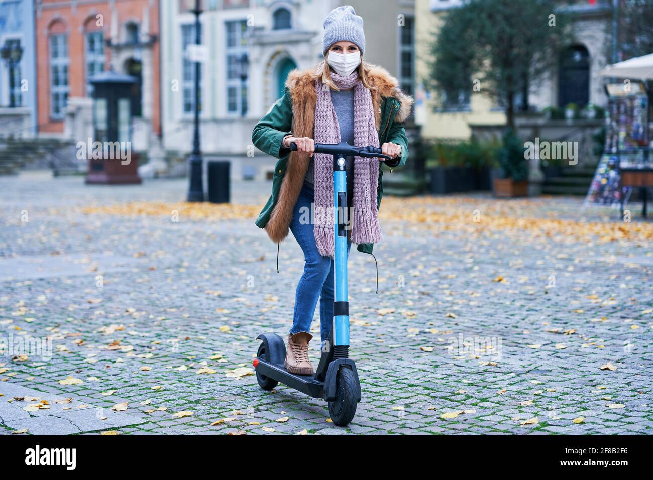 Frau trägt Gesichtsmaske und pendeln auf Roller in der Stadt Stockfoto