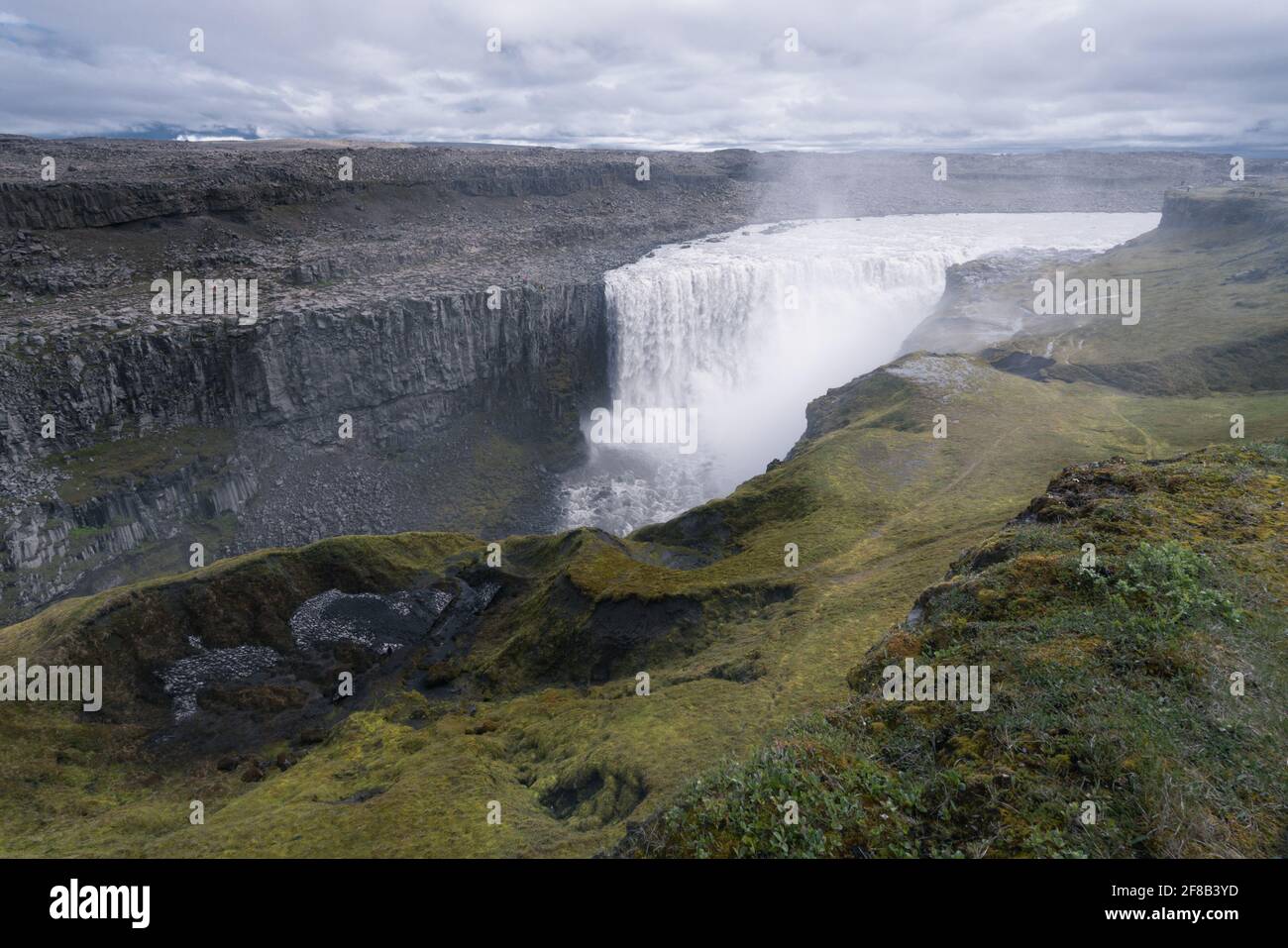 Größter Wasserfall Europas, Dettifoss. Schlammiges Wasser fällt über den Rand. Majestätischer isländischer Wasserfall an einem regnerischen, bewölkten Tag. Stockfoto