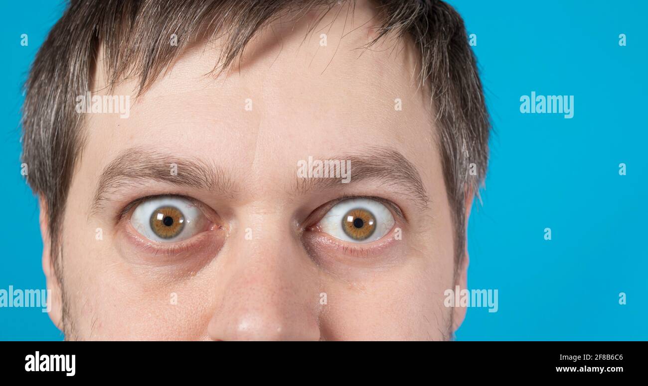 Überraschte Augen eines Mannes auf einem blauen Hintergrund Textkopie Raum. Große Augen. Um Rabatte, Verkäufe, Pfandhäuser oder Kredite zu bewerben. Stockfoto