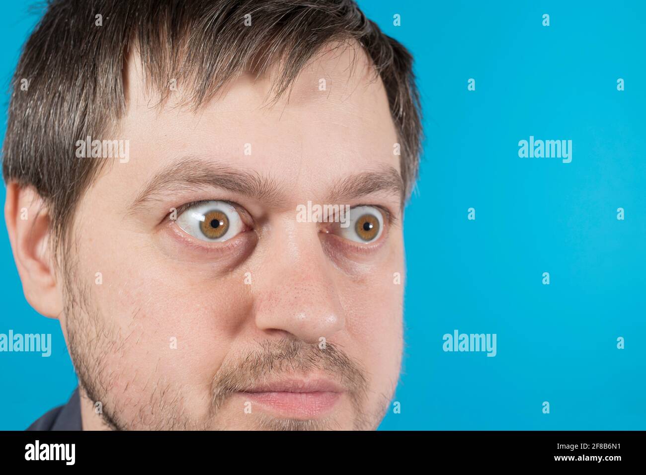 Überraschte Augen eines Mannes auf einem blauen Hintergrund Textkopie Raum. Große Augen. Um Rabatte, Verkäufe, Pfandhäuser oder Kredite zu bewerben. Stockfoto