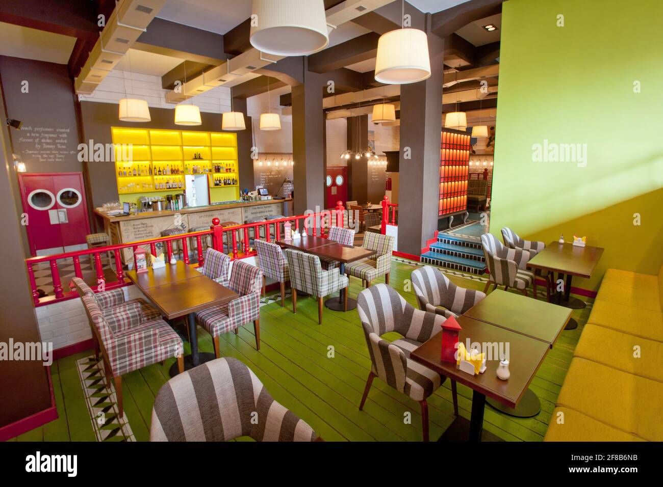 Dekorative Stühle und Tische in einer stilvollen Cafeteria mit farbenfrohen Farben Wände und moderne Lampen Stockfoto