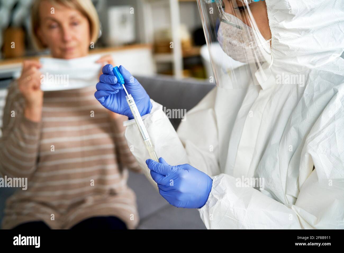 Medizinisches Personal mit Schutzhandschuhen und Arbeitskleidung, die das Reagenzglas hält Stockfoto
