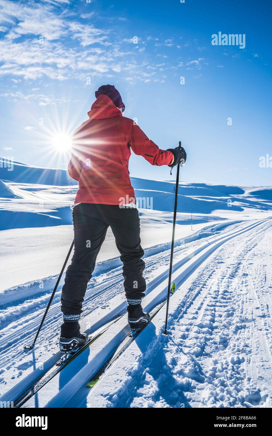 Junge Frau Skilanglauf an einem sonnigen Tag in schneebedeckten Bergen. Stockfoto