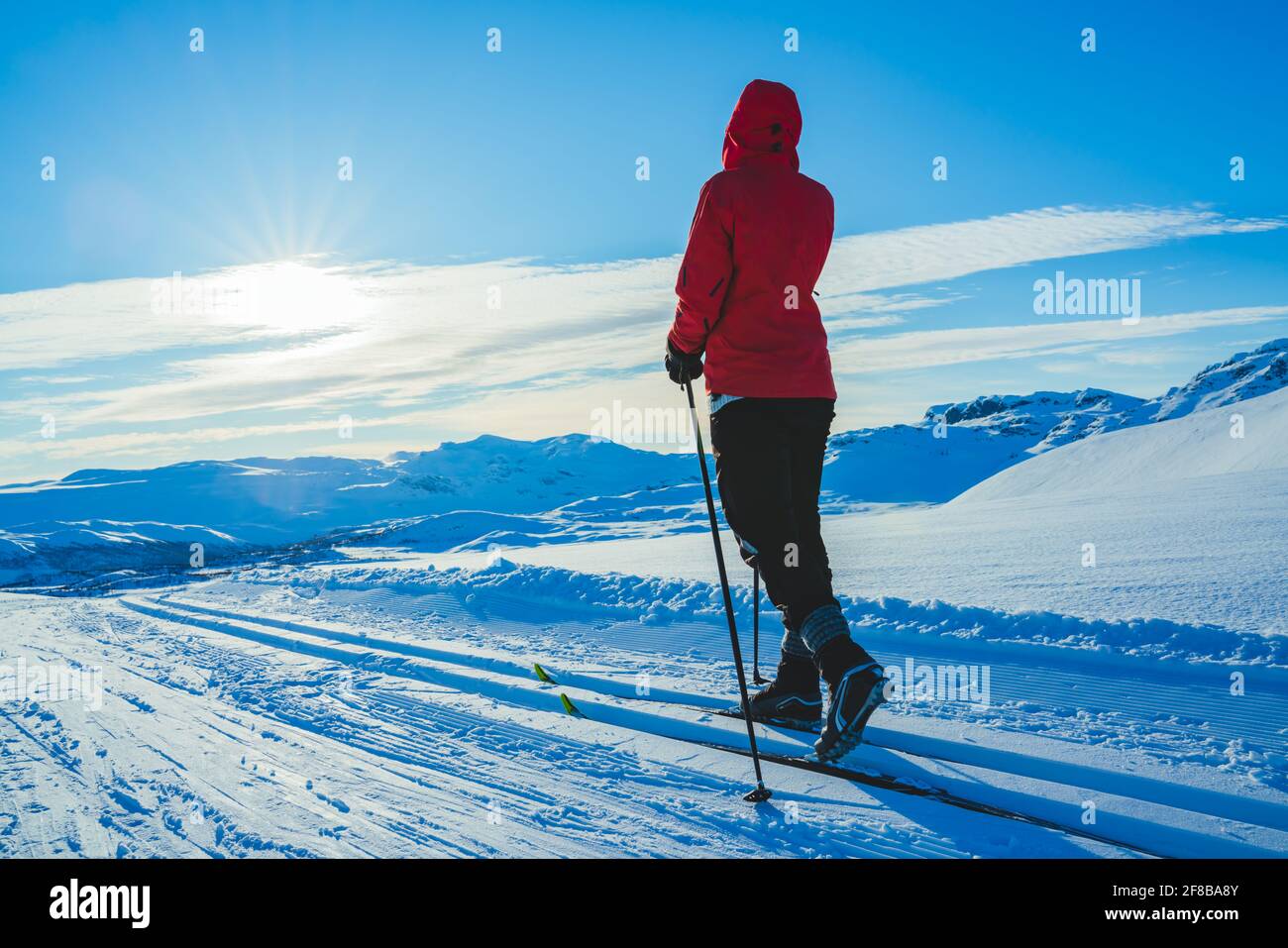 Junge Frau Skilanglauf an einem sonnigen Tag in schneebedeckten Bergen. Stockfoto
