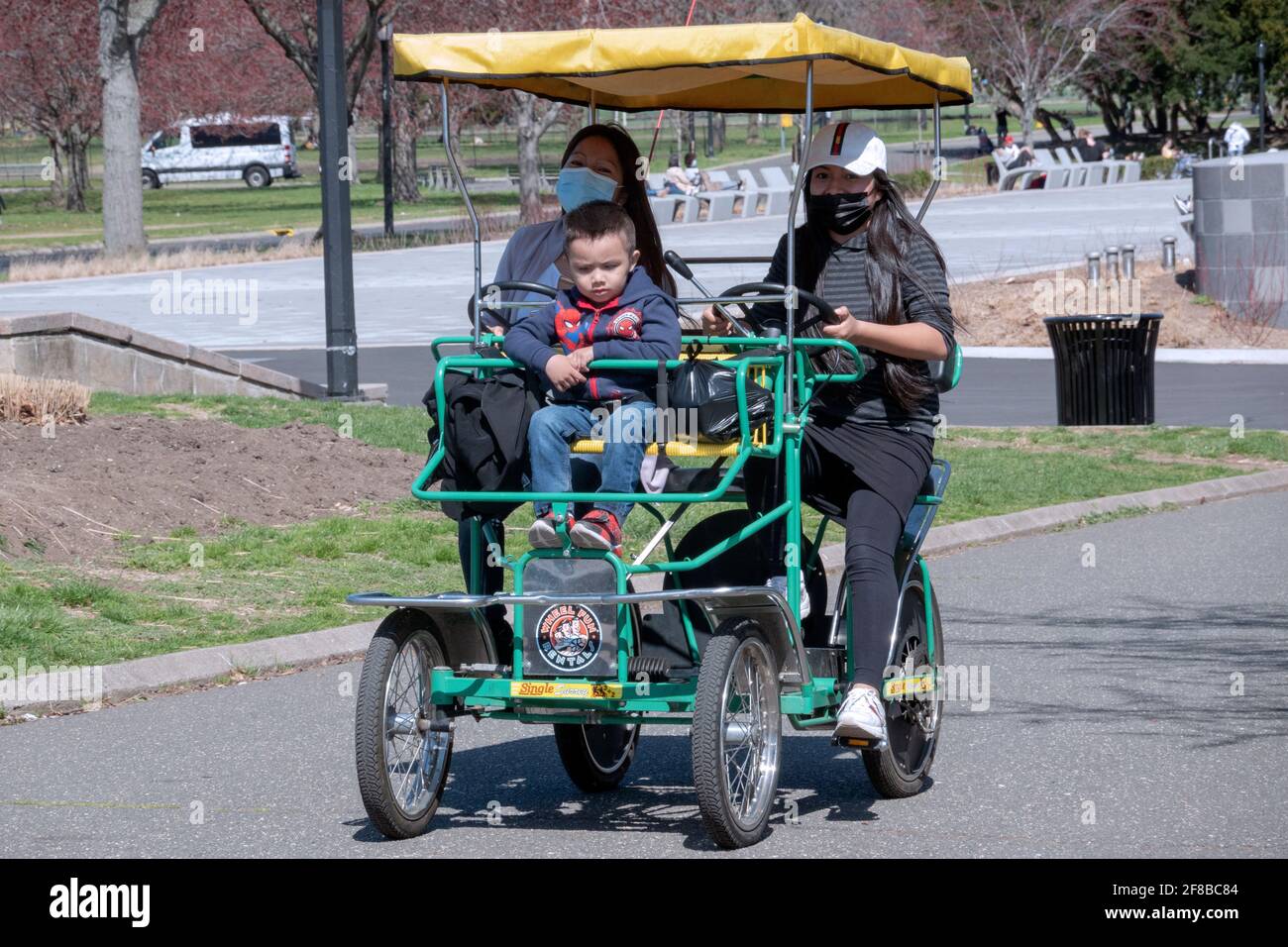 Was wie eine Familie aussieht, fährt im Flushing Meadows Corona Park in Queens, New York City, mit einem gemieteten Wheel Fun 4 Rad surrey. Stockfoto
