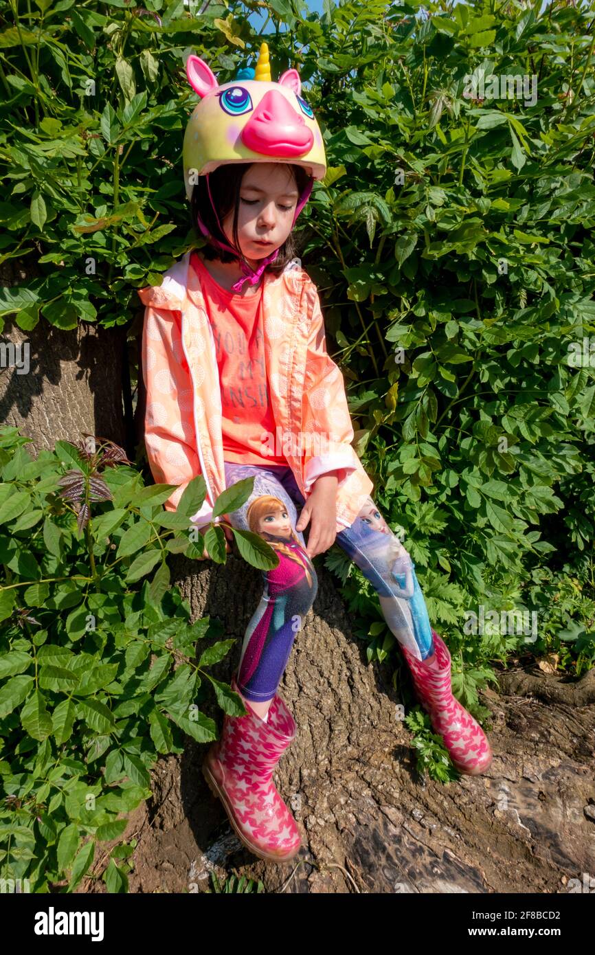 Unglückliches 8-jähriges Mädchen, das einen Raskullz-Einhorn-Fahrradhelm waring Stockfoto