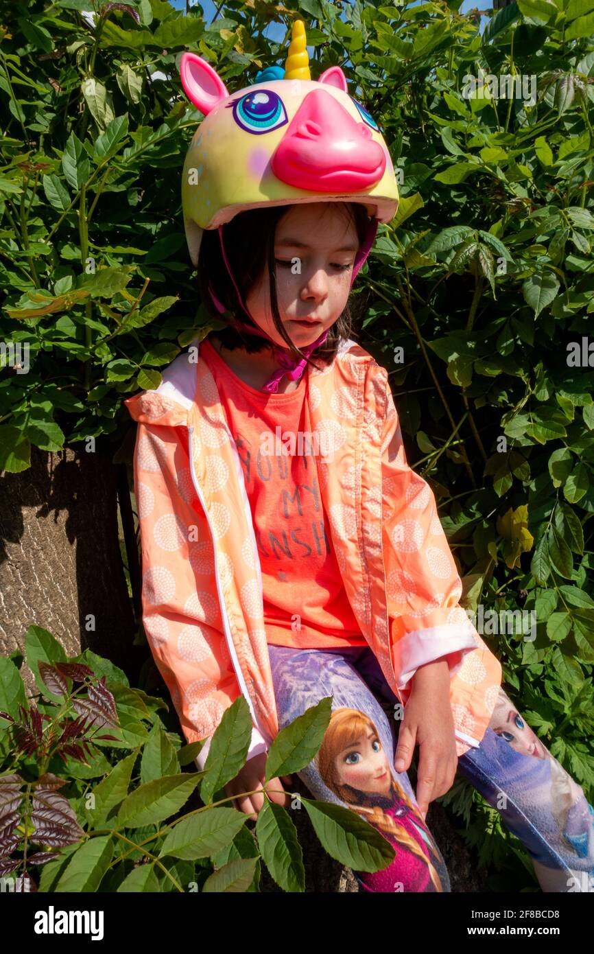 Unglückliches 8-jähriges Mädchen, das einen Raskullz-Einhorn-Fahrradhelm  waring Stockfotografie - Alamy