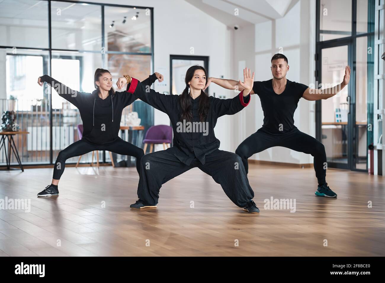 Tai Chi-Schüler mit Lehrer, die eine Peitschenform trainieren Stockfoto