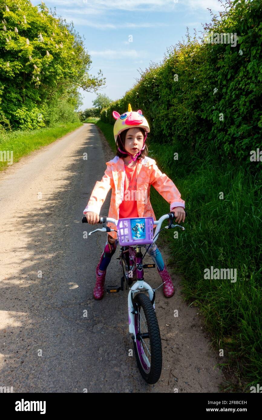 Unglückliches 8-jähriges Mädchen, das einen Raskullz-Einhorn-Fahrradhelm waring Stockfoto